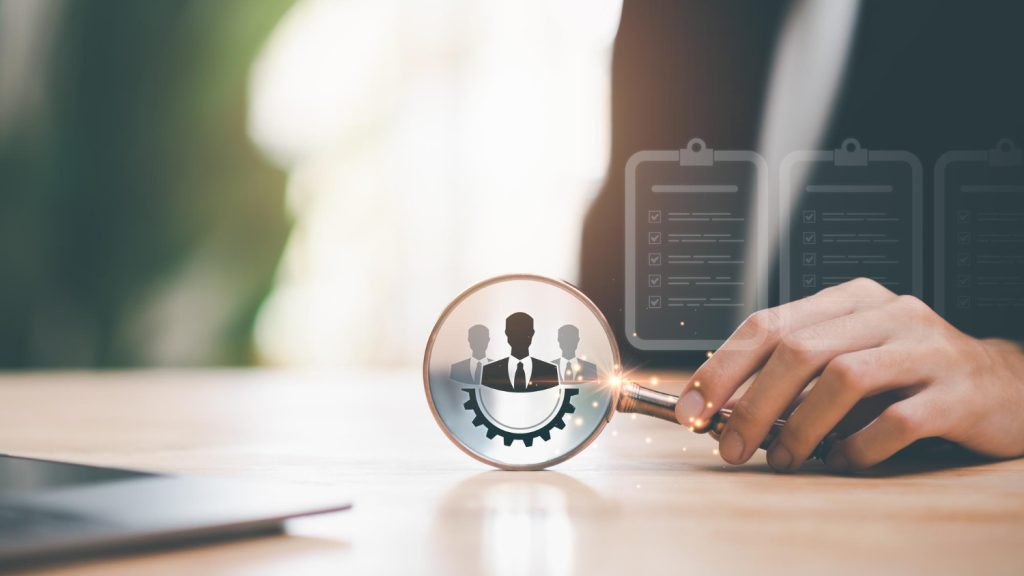 תמונה שמצגיה זכויות עובדים- זכוכית מגדלת שמראה הגדלה של 3 פרופילים של אנשים ומתחתם חצי גלגל שיניים