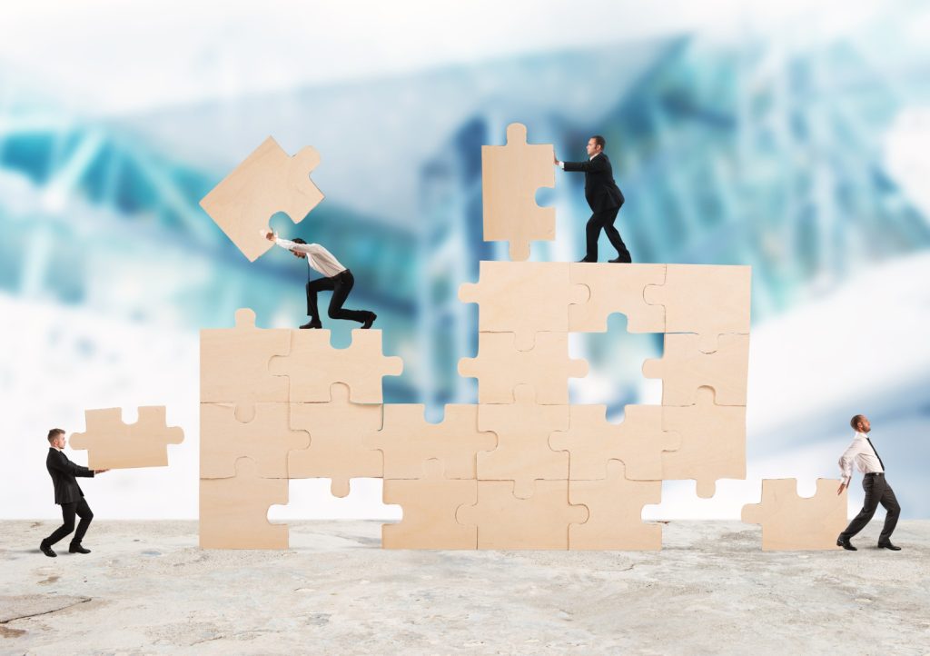 אנשית קטנים עומדים על הפאזל ובונים אותו